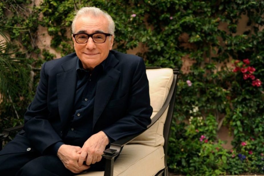 Martin Scorsese production design | Martin Scorsese Films | Director Martin Scorsese sitting in metal chair with white cushions in front of greenery in navy suit with glasses